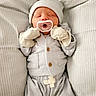 Jordan is registered to the contest to win money with this photo: baby, newborn, pacifier, mittens, hat, striped_clothing, sleeping, cushion, soft, cozy, infant, bed, resting, cute, peaceful, pajamas, child, person, indoor, portrait