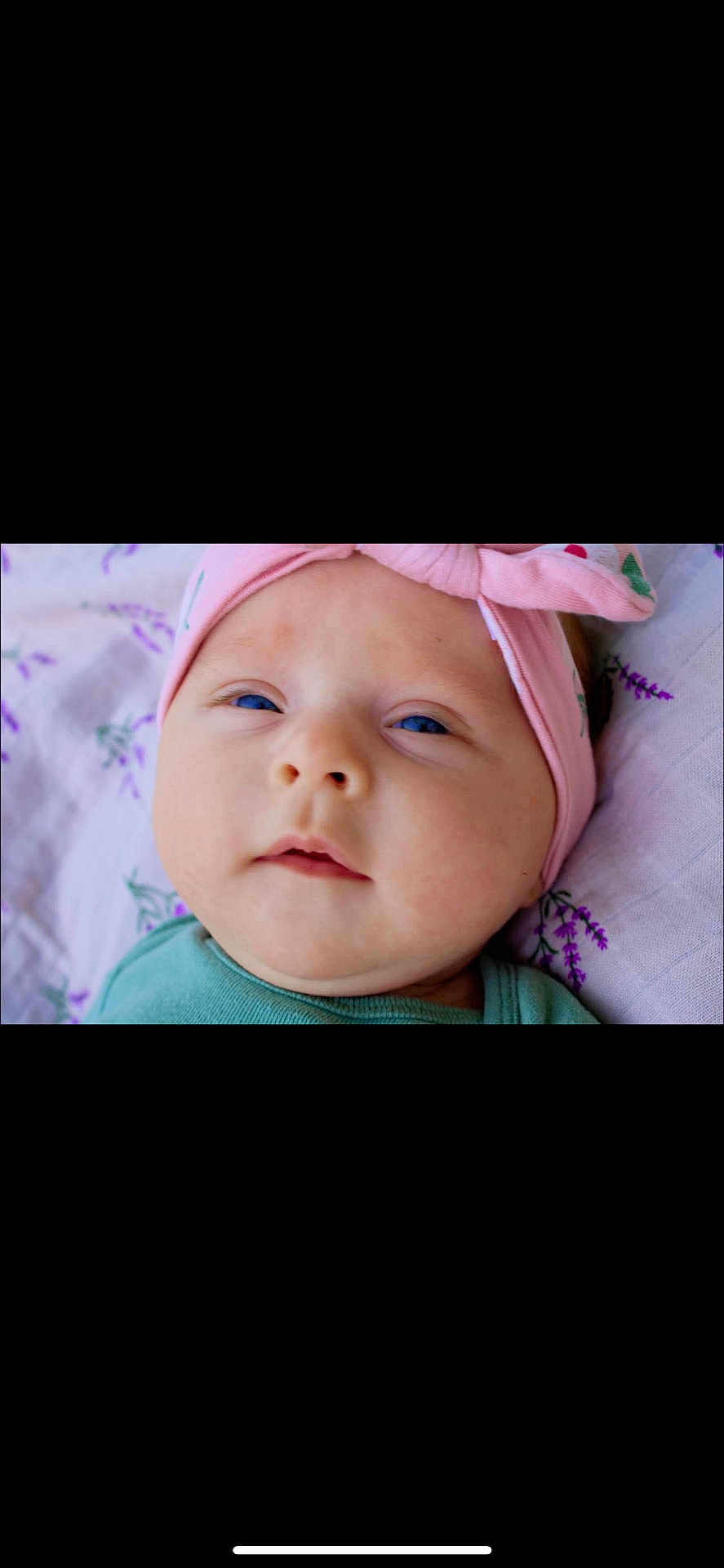 Gemma is registered to the contest to win money with this photo: baby, infant, face, headband, blue_eyes, pink, green_clothing, close_up, blanket, patterned, soft_lighting, lying_down, cute, child, newborn, portrait, skin, young, expression, indoors