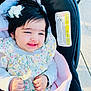 baby, child, smiling, flower_hair_clip, floral_dress, blanket, stroller, hands, face, happy, outdoor, person, cute, infant, clothing, head, skin, photography, portrait, young