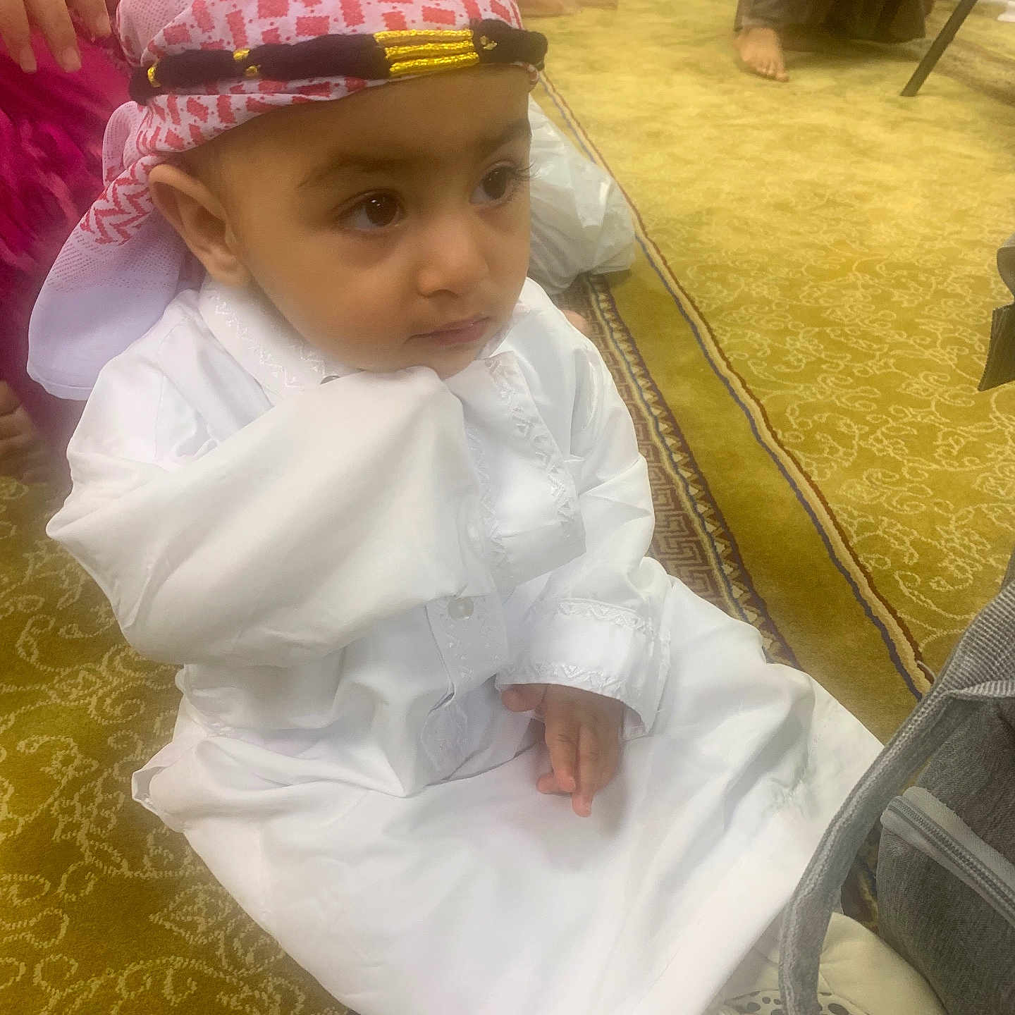 Arham joined the competition — help win amazing prizes! adult, carpet, child, closeup, cultural, curious, floor, footwear, gathering, hand, headscarf, indoor, pattern, people, person, portrait, sitting, traditional_clothing, white_clothing, young