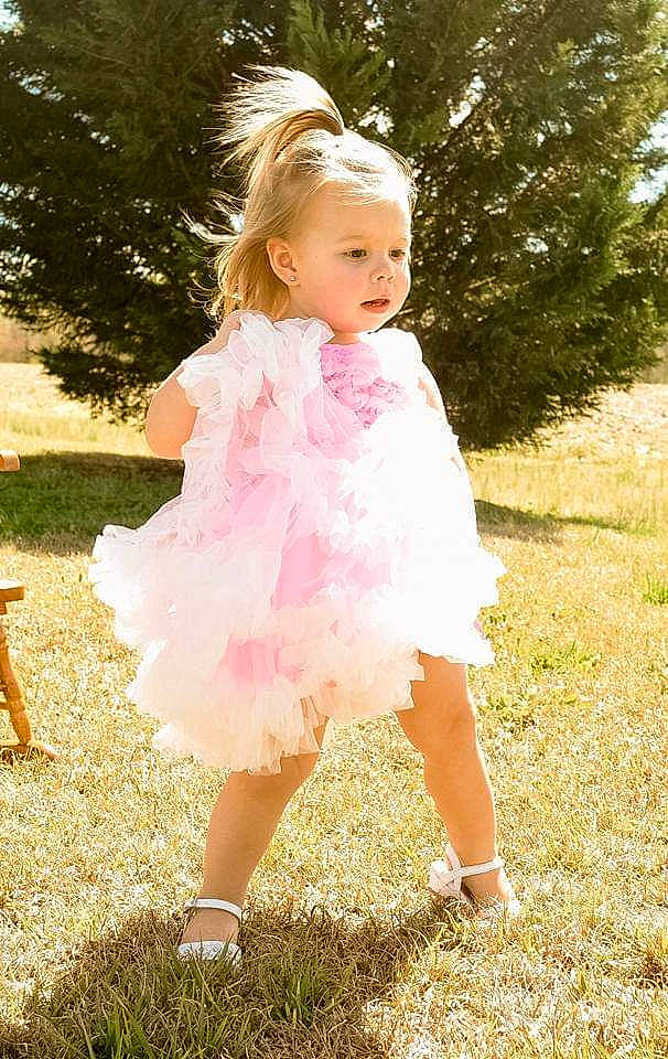Athena is registered to the contest to win money with this photo: child, dance_dress, dress, flower_girl, fun, girl, gown, grass, hair_accessory, happiness, human_hair_color, joint, person, photo_shoot, pink, shoulder, summer, toddler