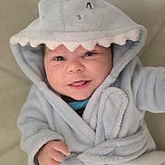 Michael is registered to the contest to win money with this photo: baby, child, smile, hood, robe, cozy, cute, infant, face, happy, portrait, blue, clothing, indoors, soft, young, babywear, expression, warm, playful