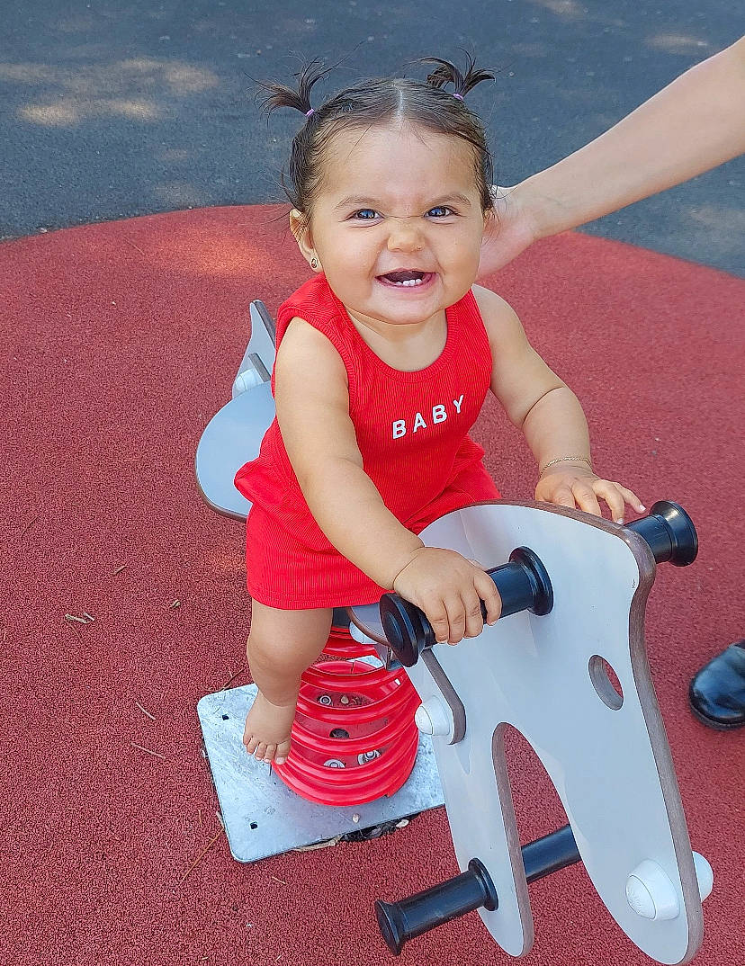 Hayna a rejoint le concours — aidez-le/la à gagner de superbes lots ! arm, baby_playing_with_toys, baby_toddler_clothing, child, face, fun, happy, human_body, human_leg, knee, leisure, person, pink, recreation, riding_toy, shoe, sitting, smile, thigh, toddler