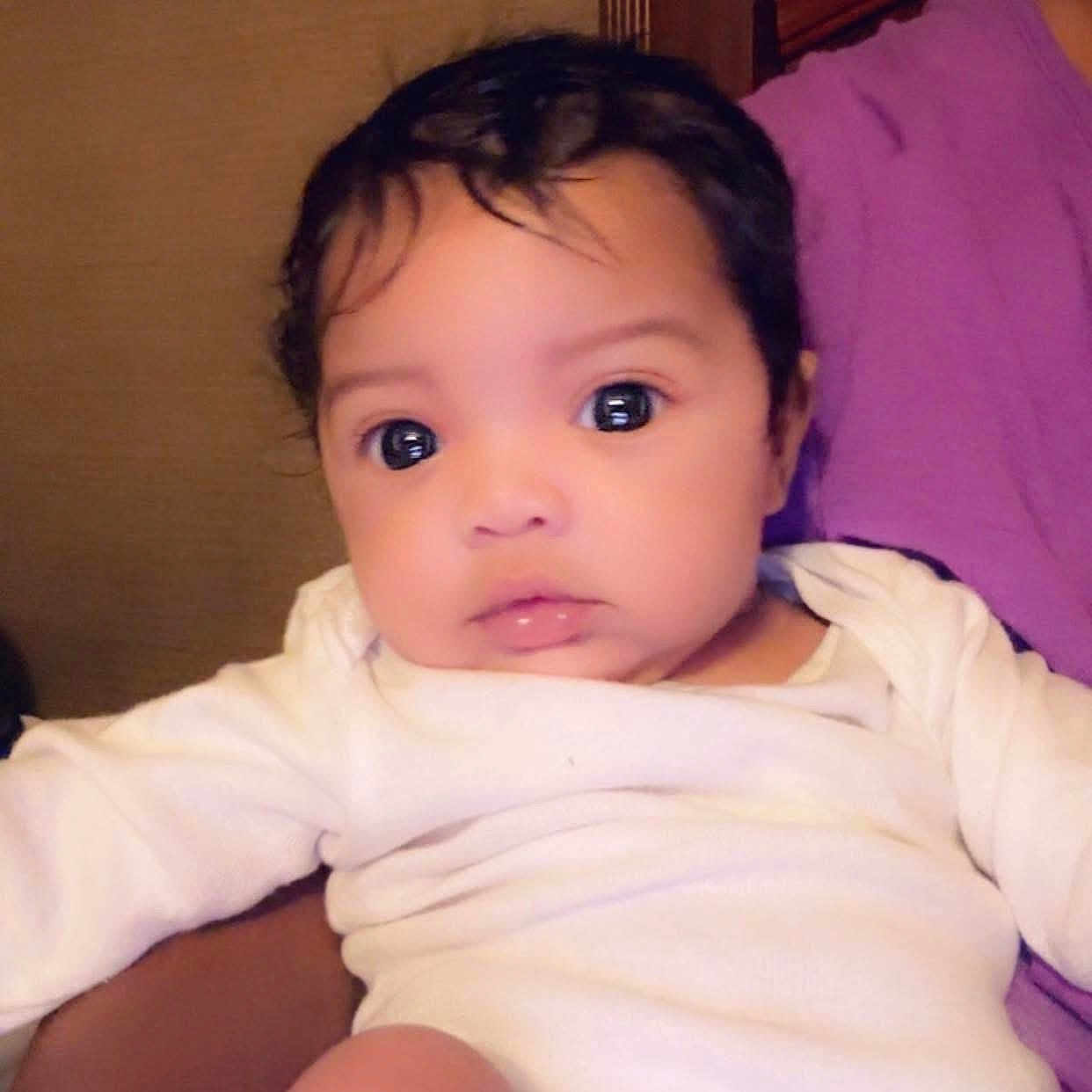 Riyonn joined the competition — help win amazing prizes! adorable, baby, child, closeup, cute, expression, eyes, face, hair, indoors, infant, newborn, person, portrait, purple_background, resting, skin, soft_lighting, white_clothing, young_child