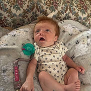 Aurora is registered to the contest to win money with this photo: baby, infant, blanket, onesie, pacifier, clothing, lying_down, indoor, cute, child, newborn, face, hand, foot, soft_texture, patterned, relaxing, young, comfort, curious
