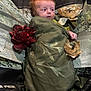 Aurora is registered to the contest to win money with this photo: baby, infant, red_hair, blanket, flower, artificial_flower, green, portrait, child, wrapped, curious, face, laying_down, background, nature_theme, photography, soft_lighting, closeup, indoor, decorative