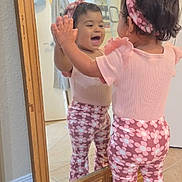Valentina joined the competition — help win amazing prizes! toddler, child, mirror, reflection, pink_clothing, headband, happy, smiling, indoor, tile_floor, wooden_frame, pants, short_sleeves, baby, home, person, cute, playful, expression, standing
