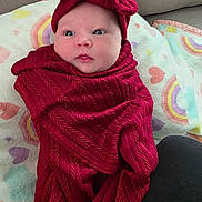 Harmony is registered to the contest to win money with this photo: baby, blanket, child, colorful, couch, cute, eyes, face, headband, heart_pattern, indoors, infant, lying_down, newborn, portrait, rainbow, red_clothing, soft_texture, swaddle, wrapped