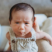 Louis is registered to the contest to win money with this photo: baby, infant, child, face, expression, knitted_clothing, closeup, human, person, cute, indoors, soft_background, holding, skin, head, eyes, mouth, hands, portrait, young