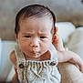 baby, infant, child, face, expression, knitted_clothing, closeup, human, person, cute, indoors, soft_background, holding, skin, head, eyes, mouth, hands, portrait, young