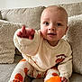 Charlie is registered to the contest to win money with this photo: baby, child, infant, blue_eyes, pumpkin, orange_socks, sitting, couch, pillow, cozy, cute, smiling, hand, sweatshirt, leggings, indoor, soft_furniture, portrait, happy, toddler