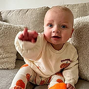 Charlie joined the competition — help win amazing prizes! baby, child, couch, sitting, clothing, socks, pumpkin, leggings, sweatshirt, cushion, indoor, smiling, cute, face, hand, person, cozy, happy, young_child, furniture