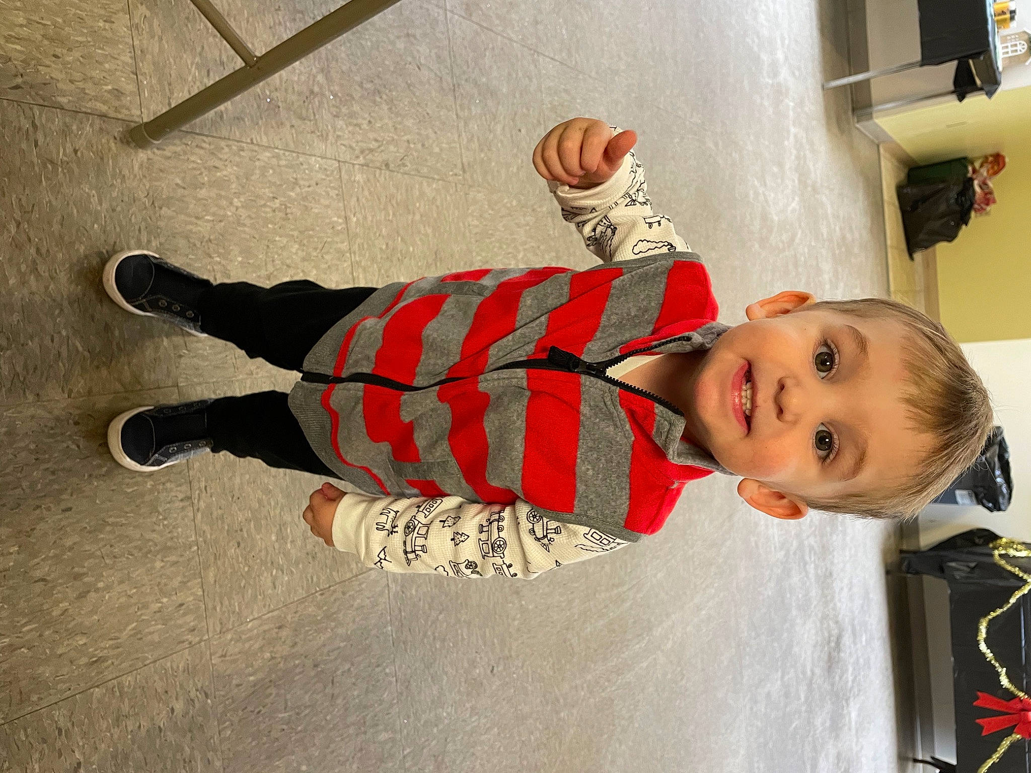 Ramsey is registered to the contest to win money with this photo: baby, baby_toddler_clothing, carmine, child, floor, flooring, fun, happy, head, holiday, joy, mammal, pattern, person, plaid, sleeve, smile, sock, toddler, tree