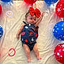 baby, infant, bow, headband, balloons, red_balloons, blue_balloons, stars, blanket, carpet, laying_down, one_arm_raised, cute, child, indoors, celebration, patterned_clothing, colorful, soft_texture, smiling