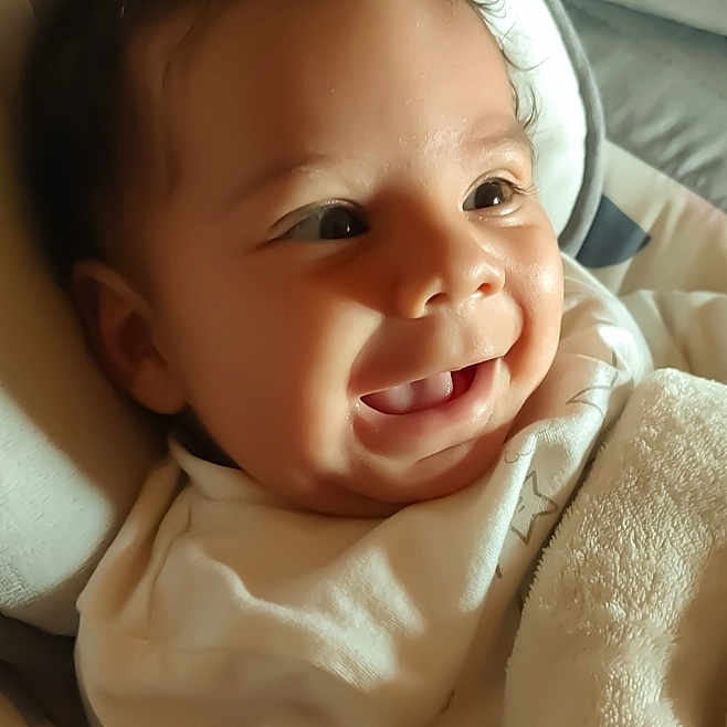 Djamaïly participe au concours pour gagner de l'argent avec cette photo : apparel, baby, blanket, child, closeup, comfort, cozy, curly_hair, cute, face, happy, indoors, infant, portrait, skin, sleeping_bed, smiling, soft_light, toddler, warm