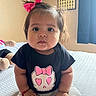 baby, child, infant, sitting, bed, pink_bow, black_shirt, skull_design, heart_eyes, red_sock, white_pants, indoors, calendar, curtains, soft_lighting, cute, portrait, young_child, hands, face