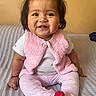 Giselle joined the competition — help win amazing prizes! baby, child, smiling, pink_vest, red_socks, white_shirt, sitting, indoors, blanket, cute, happy, portrait, face, young_child, cozy, warm_lighting, hair_tied, furniture, couch, infant