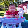 baby, child, infant, outdoor, backyard, activity_center, jumper, picnic_table, smiling, face, portrait, red_shirt, floral_pants, toy, colorful, trees, grass, shed, sunlight, family_photo