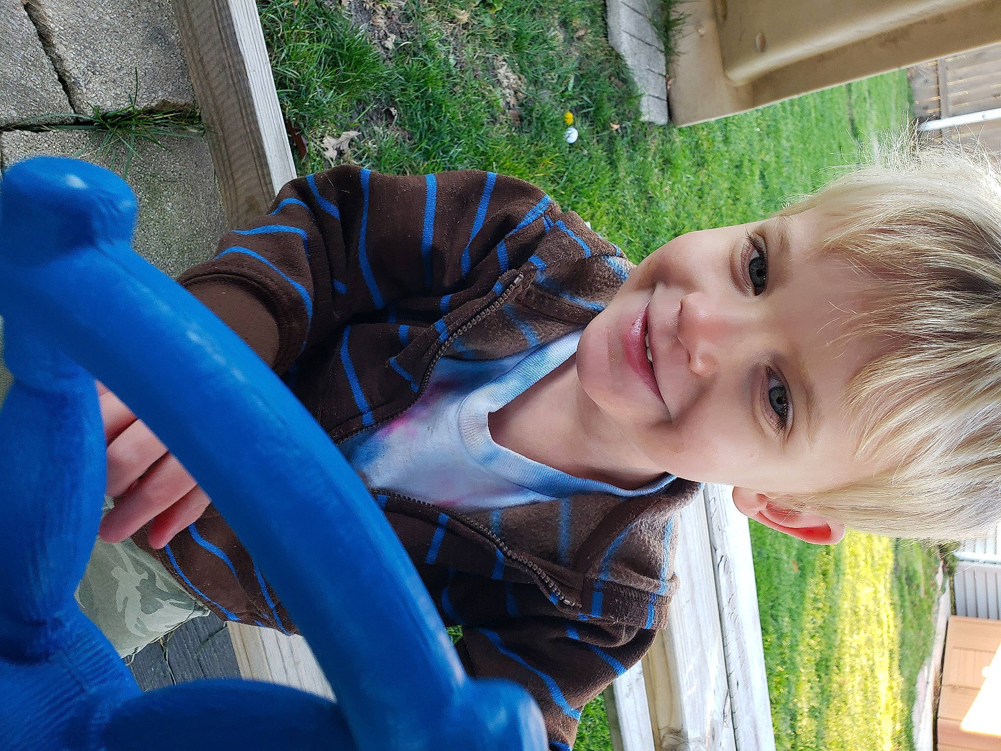 James is registered to the contest to win money with this photo: automotive_tire, blue, child, city, electric_blue, fun, grass, green, happy, human_body, human_settlement, joy, leisure, outdoor_play_equipment, person, plant, play, recreation, sitting, smile