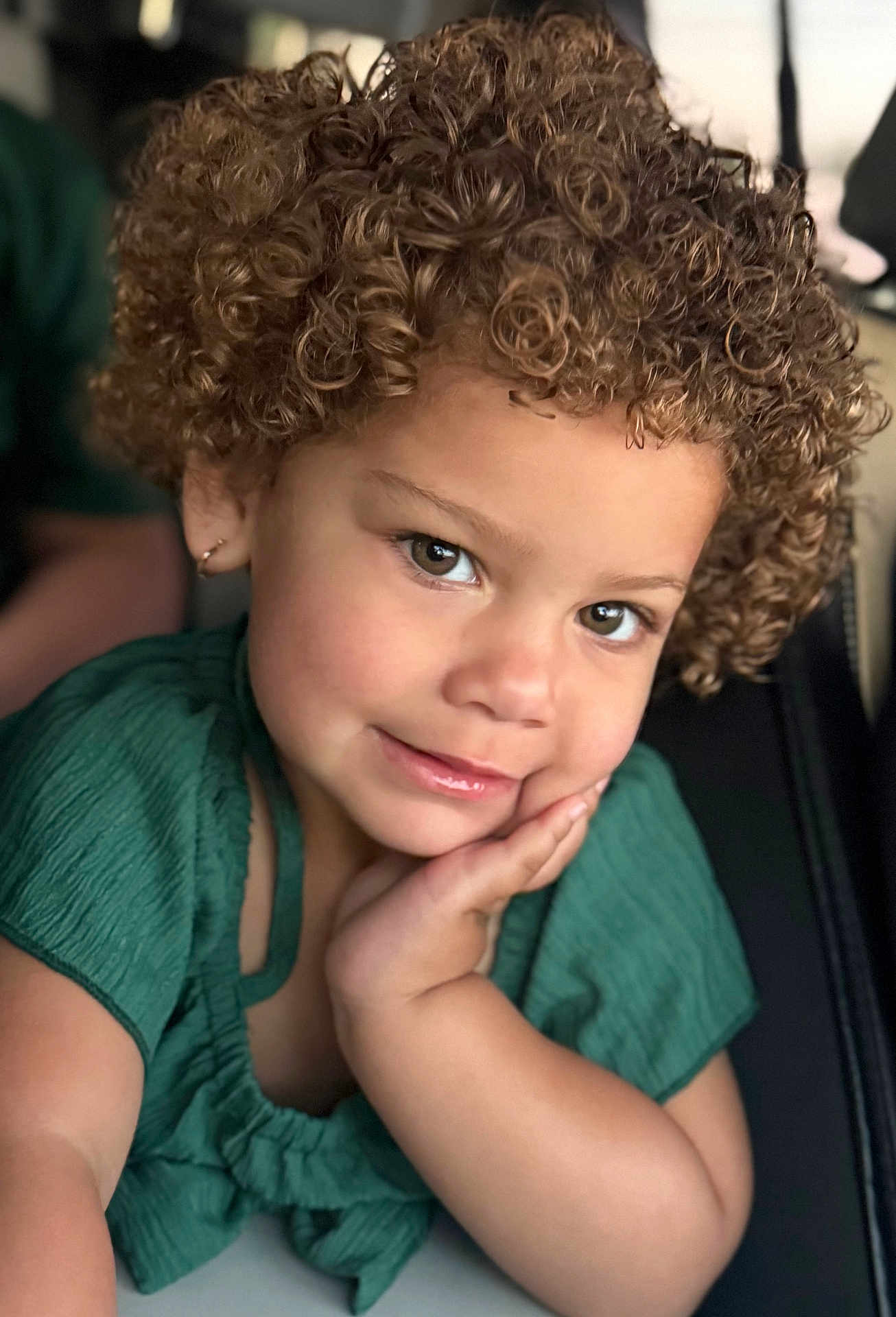 Allisson joined the competition — help win amazing prizes! child, toddler, curly_hair, green_clothing, portrait, face, smile, skin, earring, hand, cute, indoors, person, young_child, expression, eyes, hair, apparel, resting, closeup