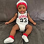 baby, infant, smiling, sitting, sofa, couch, white_onesie, jersey, number_23, jordan, hat, beanie, socks, happy, portrait, indoors, living_room, child, hands, feet