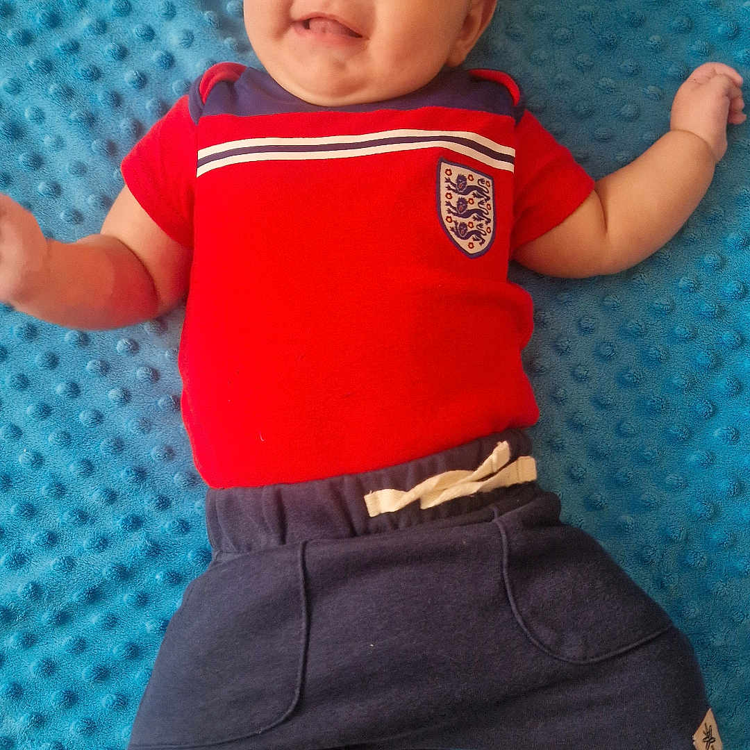 Carter-Ross joined the competition — help win amazing prizes! baby, barefoot, blue_blanket, casual_clothing, child, comfortable, cute, happy, indoors, infant, lying_down, navy_shorts, person, playful, portrait, red_shirt, small_child, smile, soft_texture, young