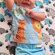 Carter-Ross is registered to the contest to win money with this photo: baby, child, smiling, blue_clothing, blanket, pattern, sheep, cartoon_animals, tiger, lion, cute, happy, infant, lying_down, indoors, person, face, head, skin, expression