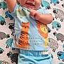 baby, child, smiling, blue_clothing, blanket, pattern, sheep, cartoon_animals, tiger, lion, cute, happy, infant, lying_down, indoors, person, face, head, skin, expression