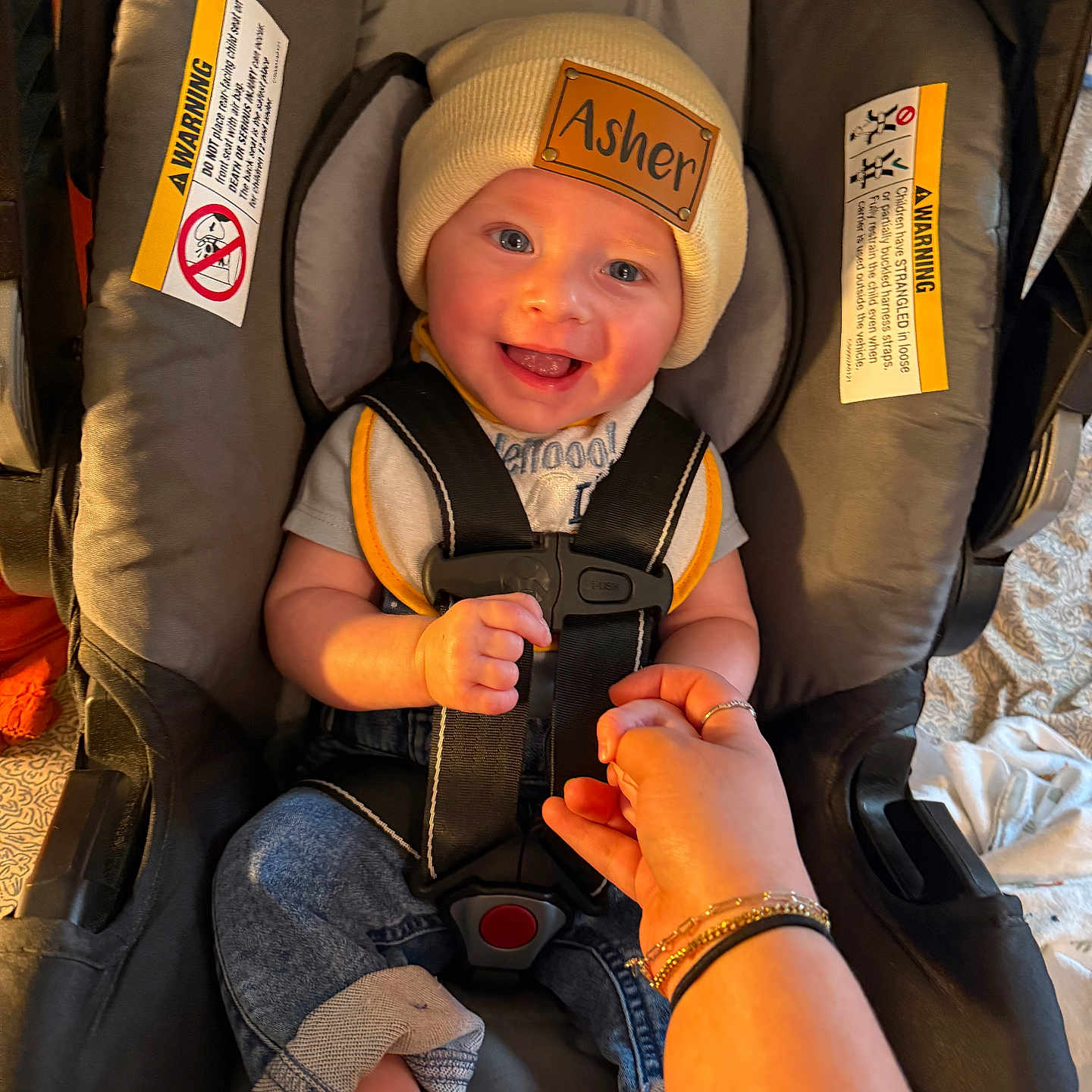 Asher is registered to the contest to win money with this photo: accessories, adult, baby, bodypart, cap, clothing, face, female, finger, hand, happy, hat, head, jewelry, person, ring, smile, transportation, vehicle, woman