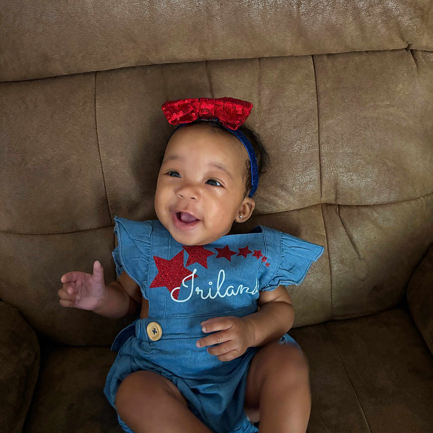 Iriland joined the competition — help win amazing prizes! baby, blue_outfit, child, clothing, couch, cute, face, furniture, happy, headband, indoor, infant, joyful, person, portrait, red_bow, sitting, skin, smiling, stars