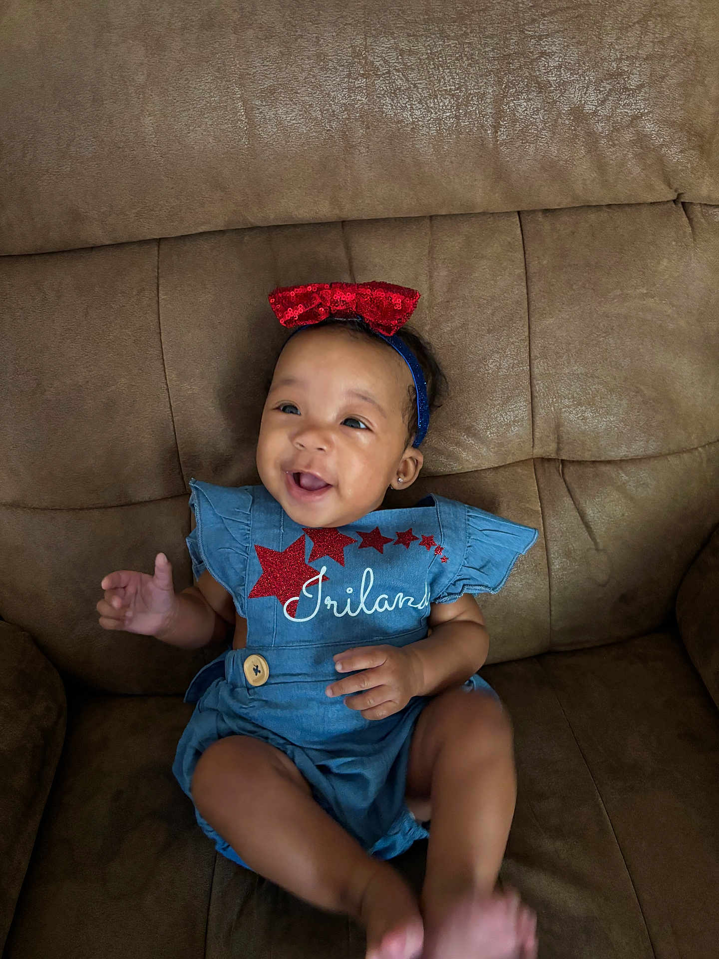 Iriland joined the competition — help win amazing prizes! baby, child, smiling, headband, red_bow, blue_outfit, stars, sitting, couch, happy, indoor, infant, cute, portrait, person, clothing, furniture, skin, face, joyful