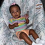 Iriland is registered to the contest to win money with this photo: baby, child, infant, face, person, sitting, clothing, shirt, shorts, socks, bow, hair, seat, pattern, fabric, indoor, cute, portrait, expression, comfort