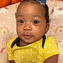 Iriland is registered to the contest to win money with this photo: baby, child, face, bow, yellow_clothing, polka_dot, earrings, cushion, unicorn_pattern, rainbow_pattern, orange_blanket, portrait, indoor, infant, cute, smiling, person, soft_toys, closeup, comfortable