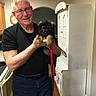 Jaeger is registered to the contest to win money with this photo: animal, black_shirt, cabinet, cute, dog, friendly, german_shepherd, glasses, happy, holding, home, indoor, kitchen, leash, man, person, pet, puppy, smile, wood_floor