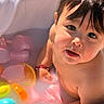 baby, child, face, skin, water, milk_bath, flower_petals, orange_slices, colorful, cute, innocence, portrait, closeup, sunlight, wet, arm, hand, reflection, bracelet, toddler