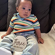 Kairo joined the competition — help win amazing prizes! baby, infant, child, three_months, sitting, striped_sweater, denim_jeans, white_shoes, blanket, couch, wooden_sign, milestone, curly_hair, indoor, portrait, cute, soft_lighting, casual_clothing, young_child, comfortable