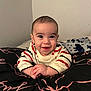Rory is registered to the contest to win money with this photo: baby, smiling, striped_sweater, lying_down, hands_clasped, bed, blanket, indoor, cute, child, happy, portrait, infant, face, young, cozy, toddler, person, expression, warm