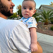 Rory is registered to the contest to win money with this photo: baby, man, outdoor, sky, suburban, house, person, holding, curious, child, portrait, daylight, side_view, casual, tshirt, tree, road, sidewalk, nature, expression