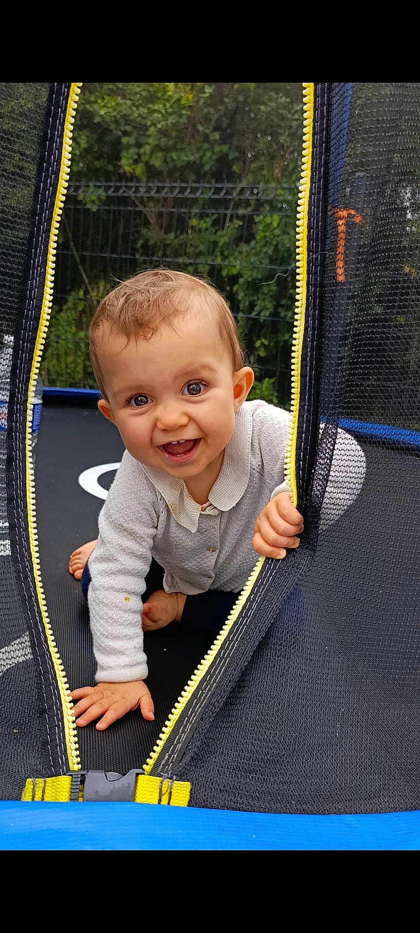 Zeylïnah a rejoint le concours — aidez-le/la à gagner de superbes lots ! baby, child, crawling, trampoline, mesh, zipper, yellow_zipper, outdoor, greenery, happy, smiling, curious, playful, young_child, infant, clothing, long_sleeve, barefoot, nature, fence