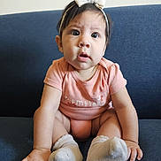 Aithana joined the competition — help win amazing prizes! baby, infant, child, onesie, headband, bow, socks, couch, blue_couch, curious, wide_eyes, sitting, indoor, portrait, person, cute, expression, clothing, skin, smile