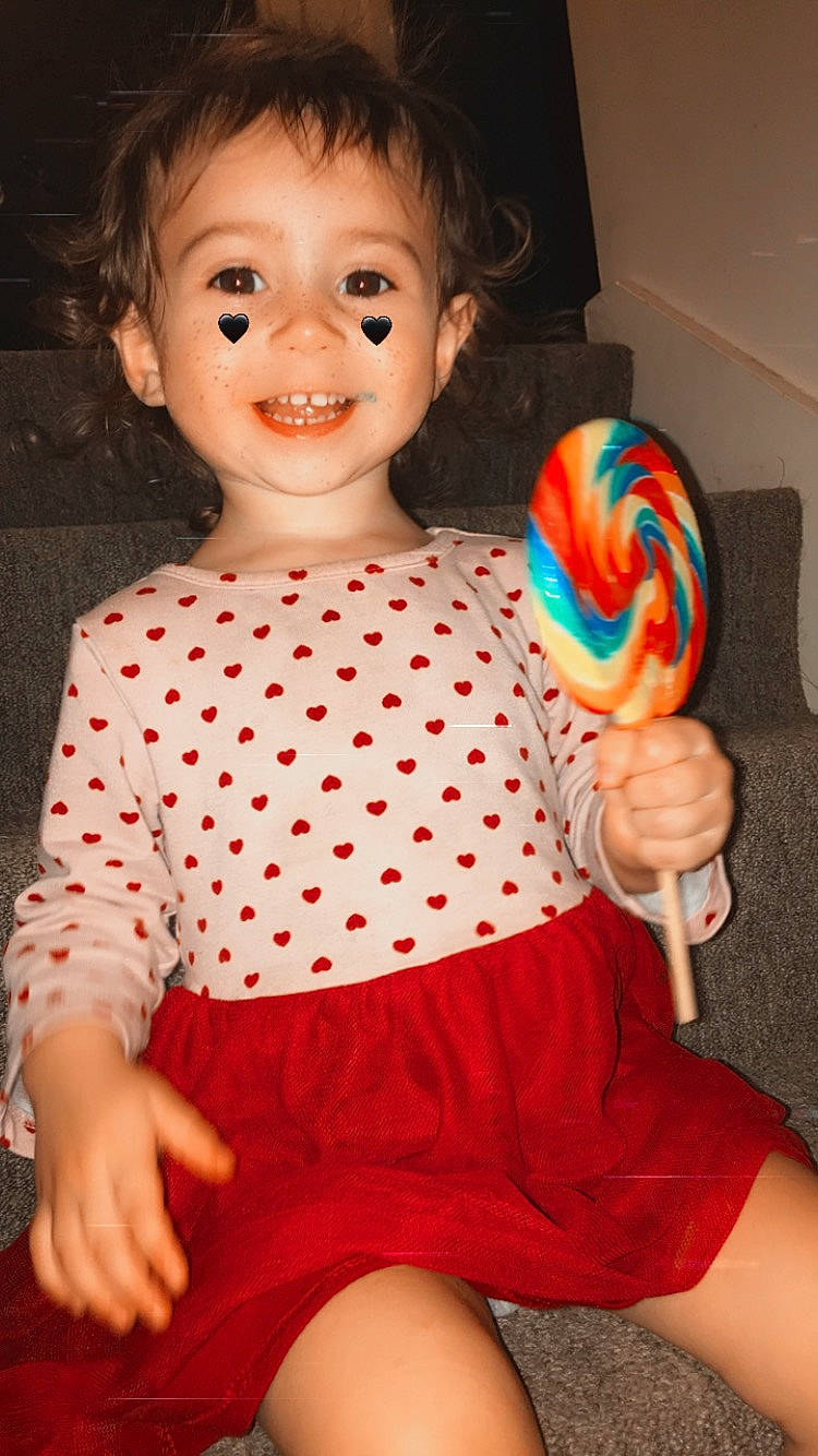 Jaylyn joined the competition — help win amazing prizes! arm, baby_toddler_clothing, child, dress, finger, hand, happy, headgear, joy, lollipop, neck, orange, organ, person, pink, shoulder, sleeve, smile, standing, textile