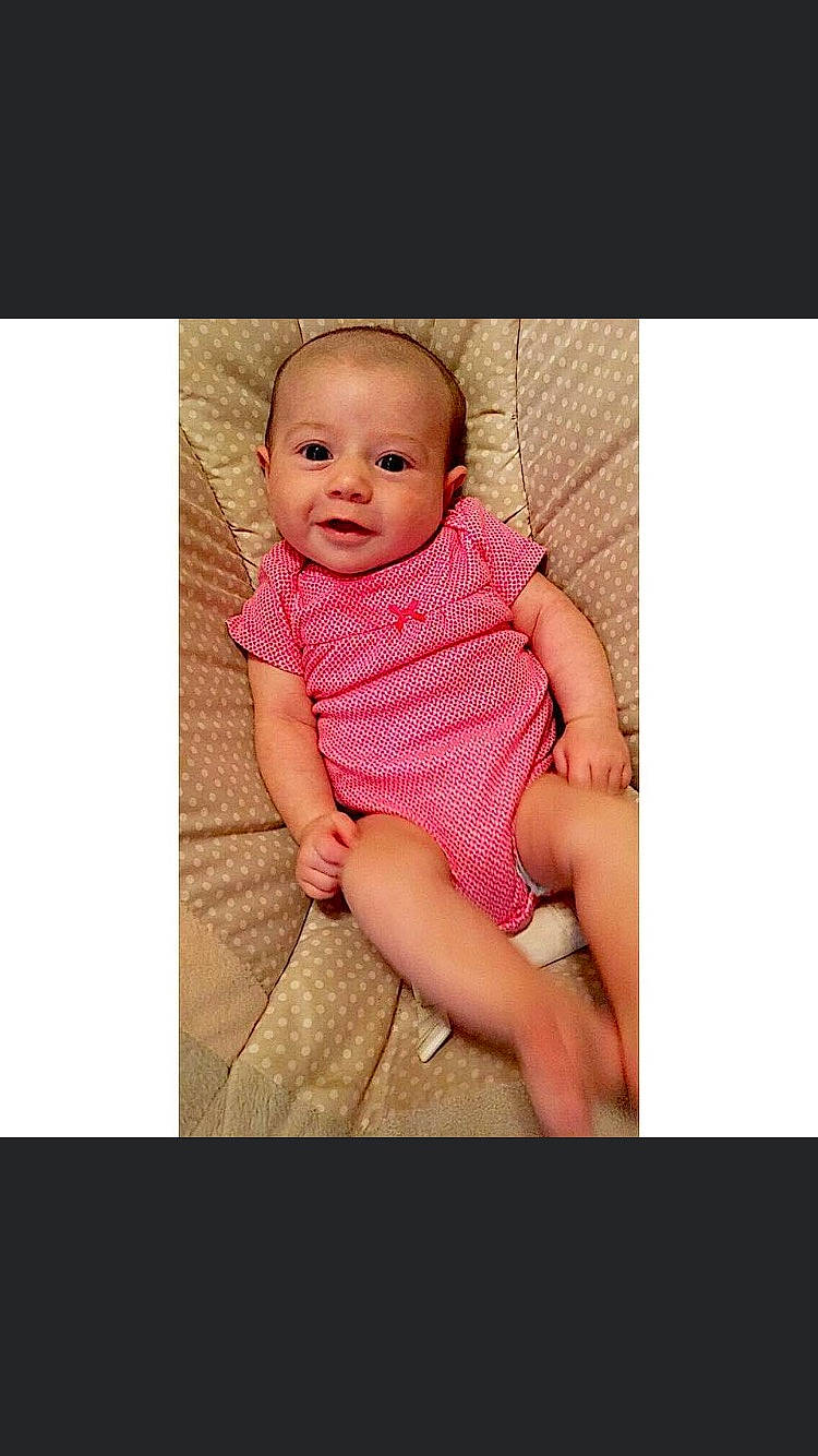 Jaylyn is registered to the contest to win money with this photo: arm, baby, baby_toddler_clothing, cheek, eye, face, flash_photography, hand, happy, head, human_body, iris, magenta, nail, neck, pattern, person, skin, sleeve, smile