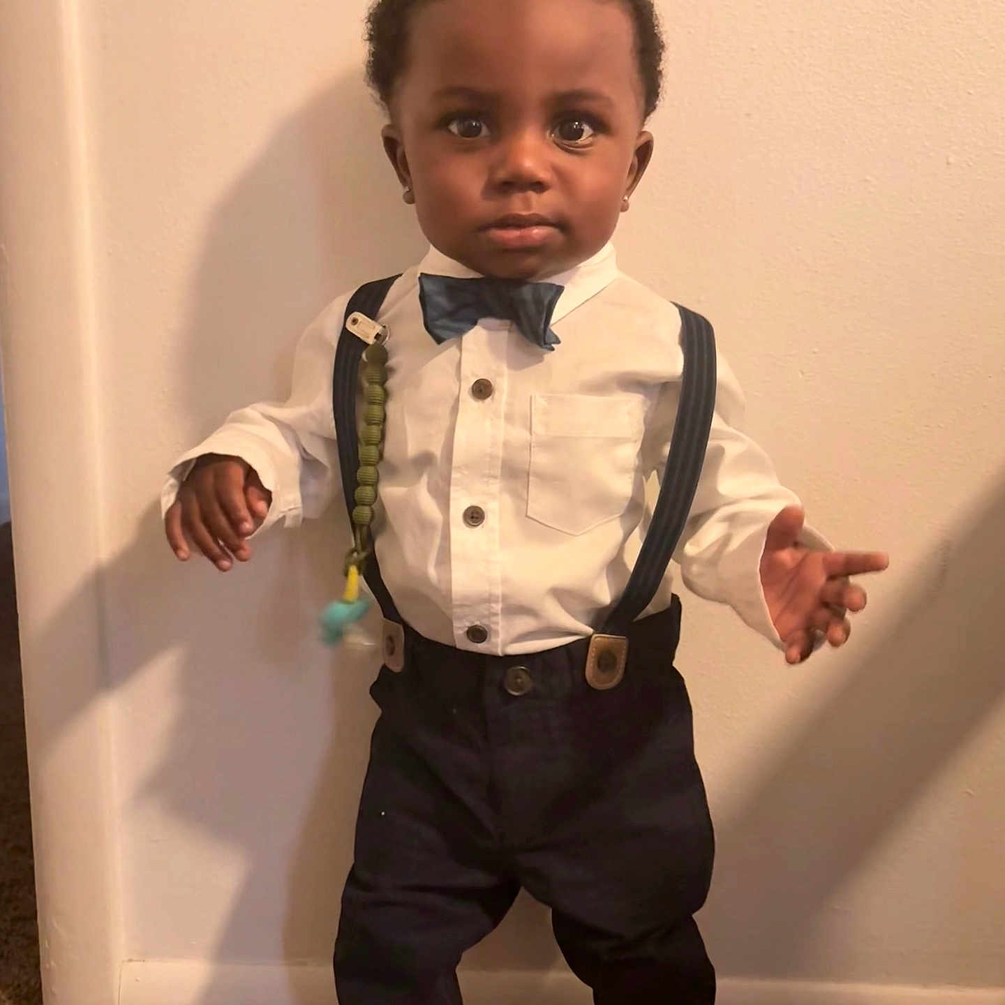 Tyrik is registered to the contest to win money with this photo: bow_tie, boy, child, clothing, cute, earrings, fashion, floor, footwear, formal_wear, indoor, pants, person, portrait, standing, suspenders, toddler, wall, white_shirt, young_child