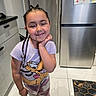 Amélia participe au concours pour gagner de l'argent avec cette photo : child, girl, braids, smile, tshirt, cartoon_character, kitchen, refrigerator, drawing, floor, tile_floor, cabinet, standing, happy, casual_clothing, home_interior, person, indoors, playful, cute