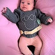 Lou a rejoint le concours — aidez-le/la à gagner de superbes lots ! baby, infant, cushion, pink, gray_sweater, knitwear, leggings, socks, face, person, child, cute, indoor, soft_texture, comfort, resting, portrait, young_child, cozy, pacifier_clip