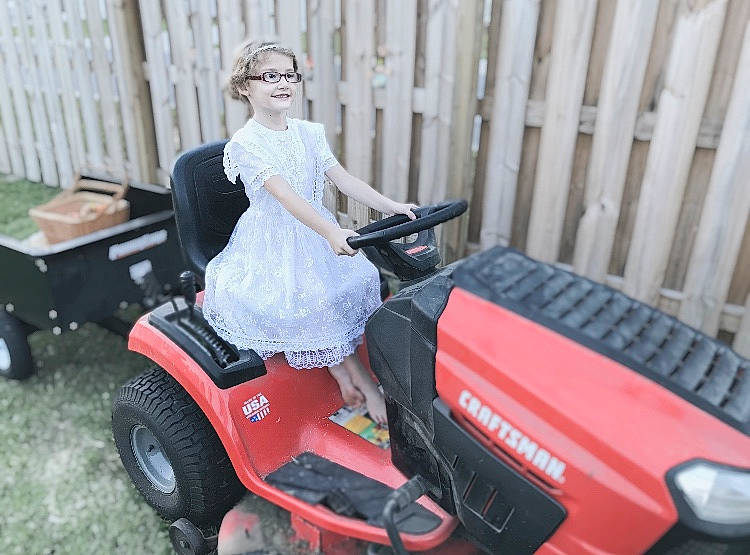 Alice is registered to the contest to win money with this photo: auto_part, automotive_design, automotive_exterior, automotive_tire, automotive_wheel_system, bumper, dress, fender, fun, grass, joy, motor_vehicle, mower, outdoor_power_equipment, person, riding_toy, rolling, tire, tractor, tread