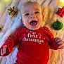 Luka is registered to the contest to win money with this photo: baby, infant, smiling, red_clothing, christmas, holiday, ornament, bow, blanket, fairy_lights, festive, celebration, happy, face, person, lying_down, cute, indoor, seasonal, toddler