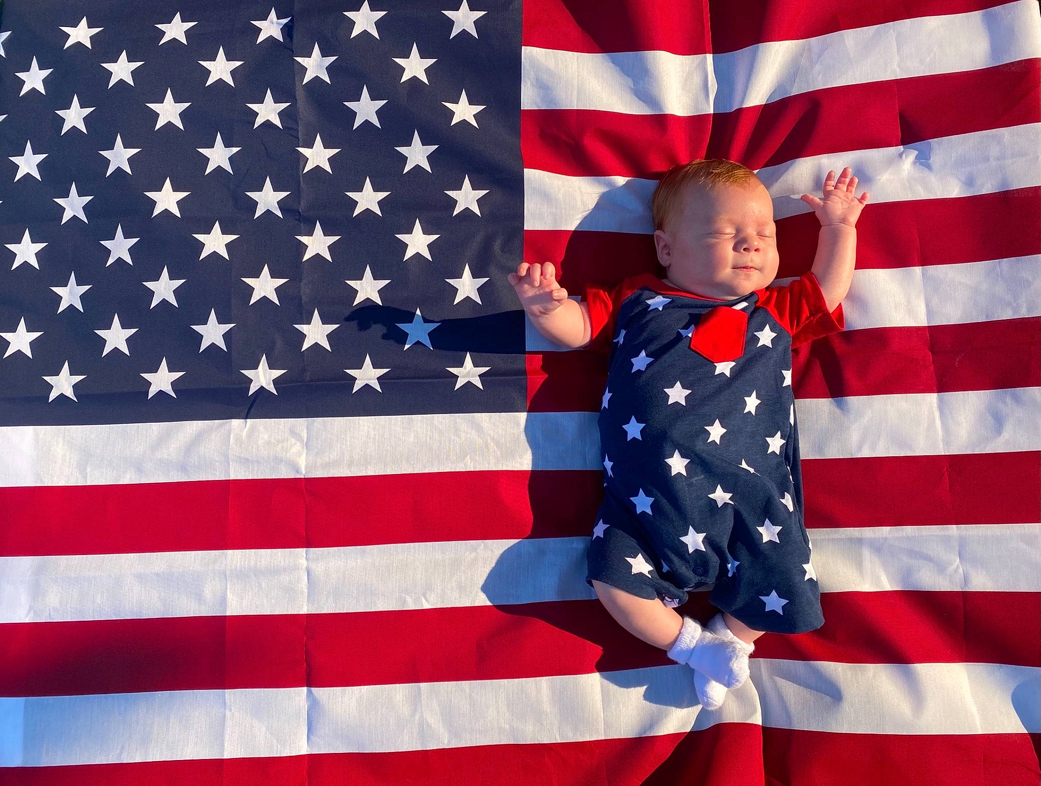 Grayson is registered to the contest to win money with this photo: blue, carmine, clothing, electric_blue, event, flag, flag_day_usa, flag_of_the_united_states, gesture, holiday, memorial_day, outerwear, pattern, person, red, sleeve, t_shirt, toddler, uniform, veterans_day