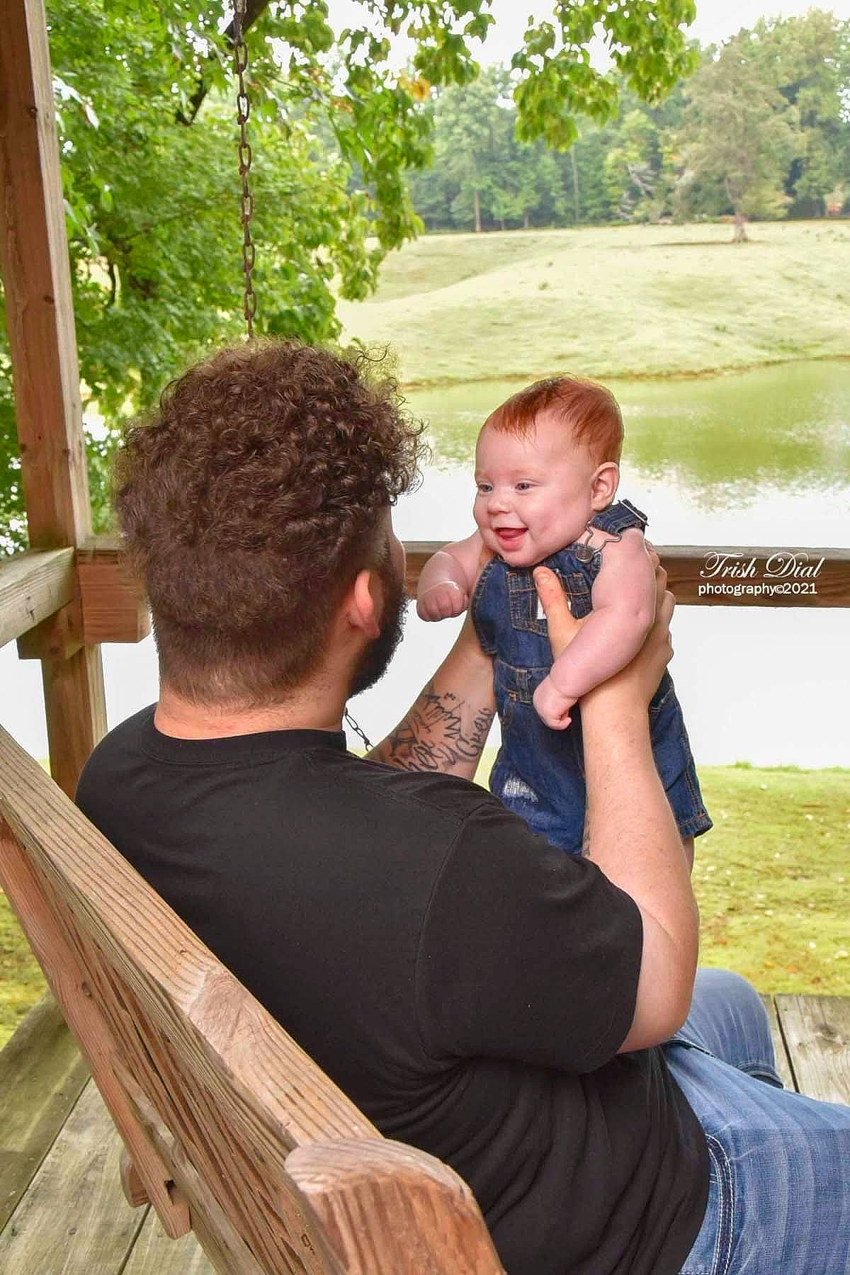 Grayson is registered to the contest to win money with this photo: baby, child, event, fun, grass, green, happy, leisure, love, people, people_in_nature, person, reading, recreation, sitting, t_shirt, toddler, tree, vacation, water