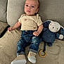 Louka participe au concours pour gagner de l'argent avec cette photo : baby, infant, child, plush_toy, blue_bunny, denim_jeans, beige_shirt, sheep_print, couch, blanket, soft_toy, footwear, casual_clothing, indoor, portrait, curious_expression, seated, wooden_ring, cute, cozy